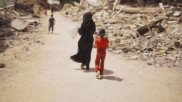 woman and girl walk amid rubble
