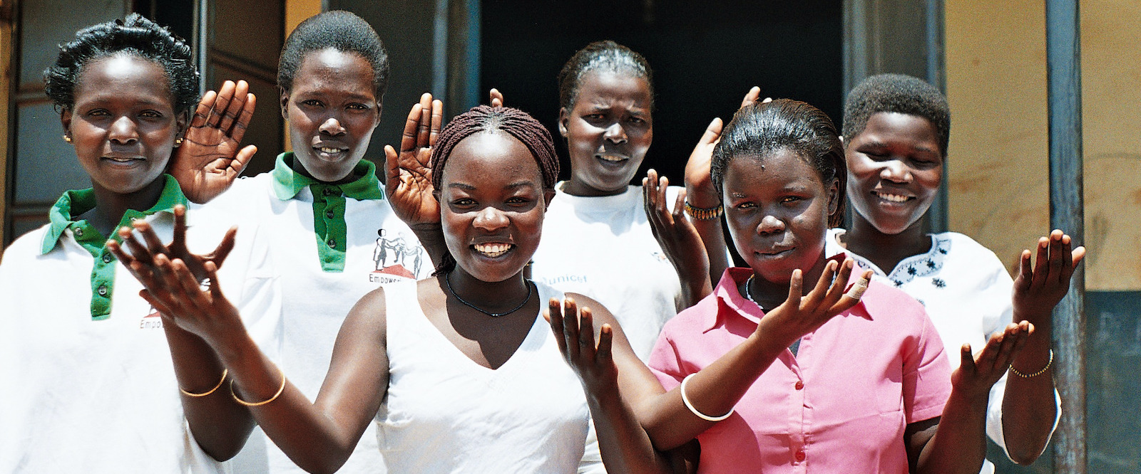 Young refugee women raise hands as a symbol of empowerment.