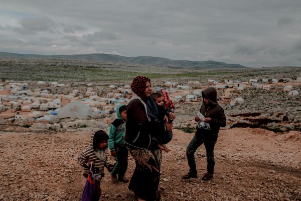 woman walking with children in refugee camp